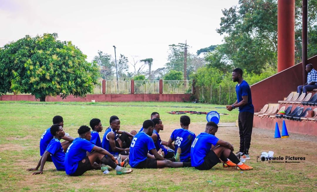 Coach speaking with seated KEDOPEACH players before training